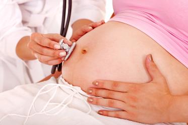 Bauch einer schwangeren Frau wird mit Stetoskop untersucht